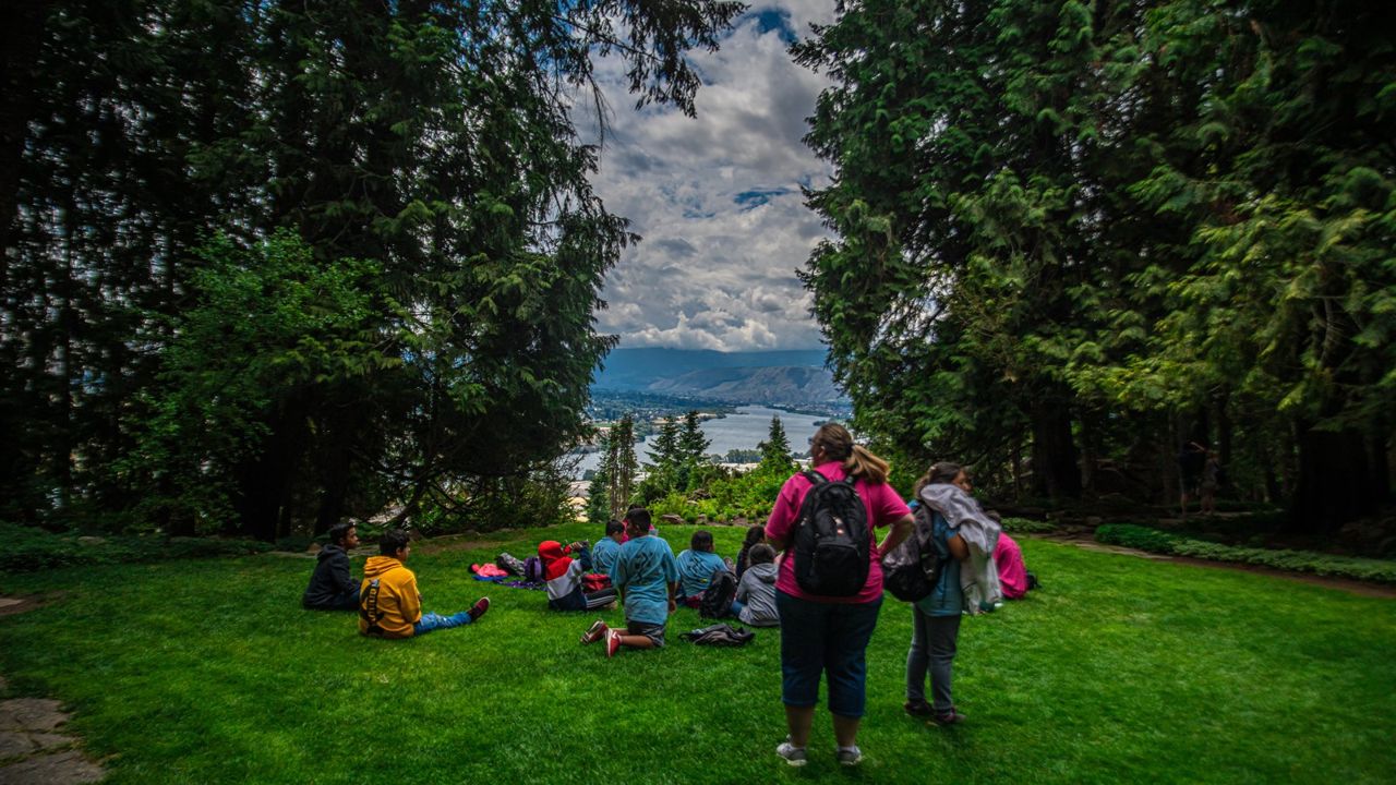 A group gathers in the grass at Ohme Gardens overlooking the Wenatchee Valley