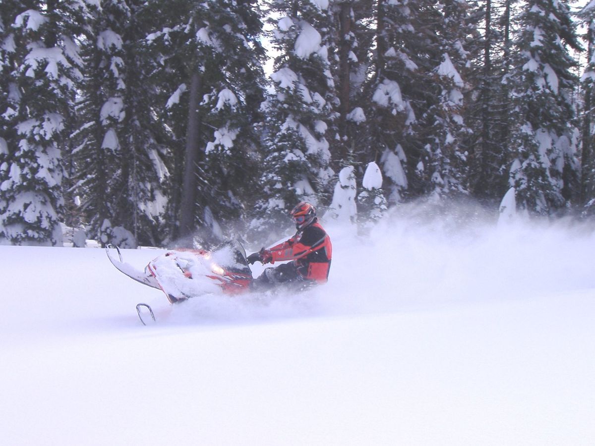 A snowmobiler maneuvers at high speed through deep powder near Hells Canyon Scenic Byway.