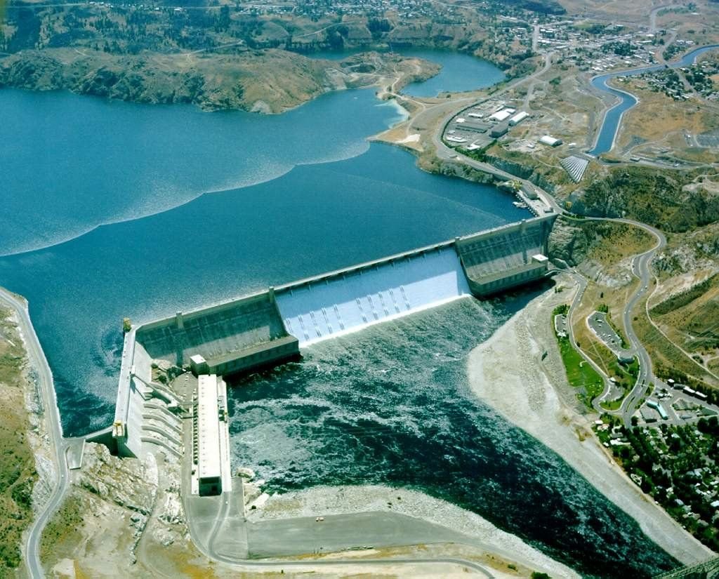 An aerial view shows the entire Grand Coulee Dam, both the concrete structure and the water behind. Its enormity is more than a picture can capture.